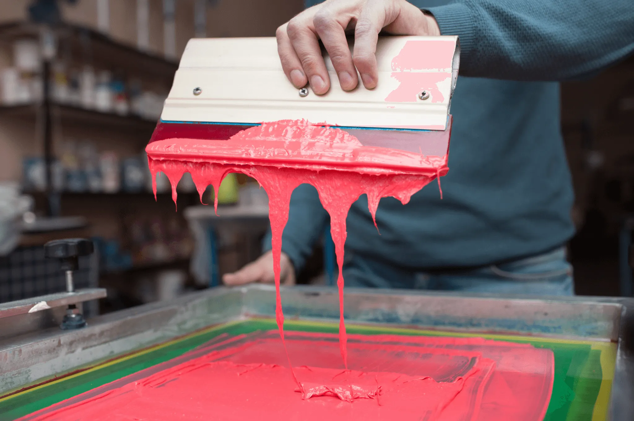Rodo puxando tinta rosa sobre a tela de silk screen
